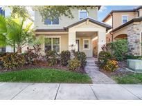 Charming two-story home with well-maintained landscaping, including a palm tree and colorful bushes at 7184 Enchanted Lake Dr, Winter Garden, FL 34787