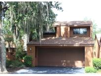 Inviting two story home with an attached garage, nestled under trees, and well-manicured landscaping at 104 Oaks Ct, Sanford, FL 32771