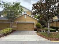 Charming townhome features a tan exterior, a two-car garage, and lovely landscaping at 14344 Desert Haven St, Windermere, FL 34786