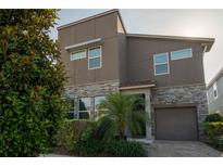 Contemporary two-story home with stone accents, neutral siding, and mature landscaping at 1836 Sandy Park Trl, Kissimmee, FL 34747