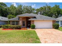 Charming single-story brick home featuring a well-manicured lawn and a brick-paved driveway leading to a two-car garage at 2085 Friar Tuck Ln, Orange City, FL 32763