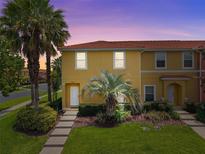 Charming townhome with a red tile roof, lush landscaping, and a well-maintained lawn at 3002 Secret Lake Dr, Kissimmee, FL 34747