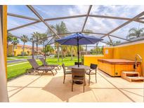 Relaxing screened patio with lounge chairs, dining table, umbrella, and a private hot tub at 3002 Secret Lake Dr, Kissimmee, FL 34747