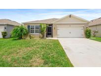 Well-maintained lawn and landscape adorn this single-story home with a two car garage in this exterior home view at 341 Alexzander Way, Winter Haven, FL 33881