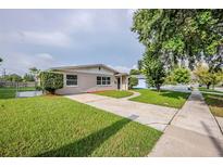 A charming single-story home boasts a well-manicured lawn, a paved driveway, and lush landscaping at 4200 Colony Way, Orlando, FL 32808