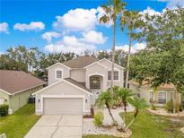 Beautiful two-story home with a well-manicured lawn and tall palm trees at 4993 Hook Hollow Cir, Orlando, FL 32837