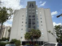 Modern condominium building featuring an elegant entrance and large windows, surrounded by lush landscaping at 6165 Carrier Dr # 1801, Orlando, FL 32819
