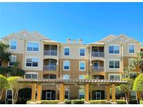 Three-story tan building with white window trim and balconies under a blue sky at 6451 Old Park Ln # 407, Orlando, FL 32835