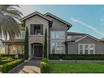 Beautiful home featuring a stone facade, manicured landscaping, and a brick walkway leading to the front door at 7550 John Hancock Dr, Winter Garden, FL 34787