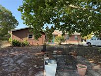 Cozy single-story house with a turquoise front door and an outdoor patio area, shaded by a large tree at 11314 Huggins St, Leesburg, FL 34788