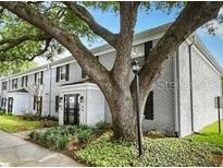 View of the building's exterior with nice landscaping, mature trees, and white painted brick at 141 Lewfield Circle # 141, Winter Park, FL 32792