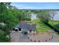 Stunning aerial view of the lakefront home with a pool, cabana, lush landscaping, and a circular driveway at 1700 Lake Markham Rd, Sanford, FL 32771