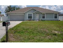 Charming single-story home featuring a well-maintained lawn, attached garage, and welcoming front entrance at 1858 Snapper Dr, Poinciana, FL 34759