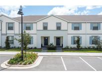Charming townhome featuring a light exterior, blue shutters and well-maintained landscaping at 2439 Dubai St, Kissimmee, FL 34747