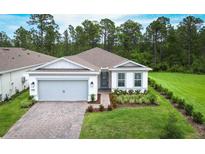 Charming single-story home featuring a two-car garage, brick driveway, manicured lawn and lovely landscaping at 2479 Pine Preserve Ct, St Cloud, FL 34771