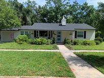 Charming single-story home with a well-manicured lawn, lush landscaping, and a light blue front door at 251 Glenridge Way, Winter Park, FL 32789