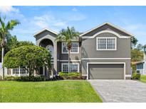 Beautiful two-story gray home with lush landscaping, manicured lawn, and a paved driveway at 4065 Shadowind Way, Gotha, FL 34734