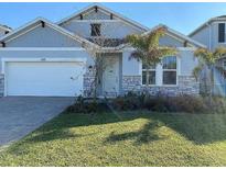 Charming single-Gathering home with manicured lawn, stone accents, and attached two-car garage at 605 Big Pine Ave, Minneola, FL 34715
