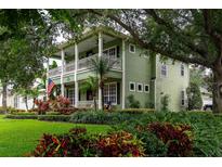 Two-story home featuring a well-manicured lawn with lush garden beds and mature trees at 8335 Lake Burden Circle, Windermere, FL 34786
