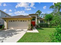 Charming single-story home with a two-car garage, red front door, and well-manicured lawn at 848 Magnolia Creek Cir, Orlando, FL 32828