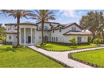 Stunning exterior elevation of home, features a circular entryway with columns, a lush yard, and meticulous landscaping at 9259 Tibet Pointe Cir, Windermere, FL 34786