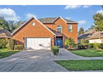 Charming two-story brick home with a well-manicured front yard, a garage, and a welcoming blue front door at 9455 Belmont Ter, Oviedo, FL 32765