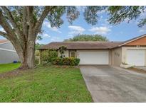 Charming single-story home featuring an attached two-car garage, mature trees, and lovely landscaping at 106 Water Oak Dr, Sanford, FL 32773