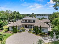 Breathtaking lakefront estate with lush landscaping and circular driveway, showcasing the home's elegance at 1112 Preserve Point Dr, Winter Park, FL 32789
