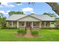Charming home featuring a metal roof, inviting front porch, and meticulously landscaped yard at 17523 Doris St, Montverde, FL 34756