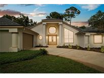 Stunning home exterior featuring a well-manicured lawn, double doors, and architectural pillars at sunset at 388 Hampton Hills Ct, Debary, FL 32713
