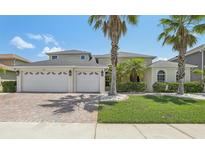 Charming two-story home showcasing a three-car garage, a lush green lawn, and beautiful tropical landscaping at 827 Timber Isle Dr, Orlando, FL 32828