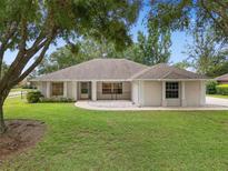 Charming single-story home featuring manicured lawn, mature trees, and neutral exterior paint at 11648 Grand Bay Blvd, Clermont, FL 34711