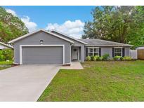 Charming single-story home features a well-manicured lawn, neutral gray paint, and a two-car garage at 122 Seville Rd, Auburndale, FL 33823