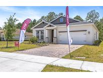 Well-manicured front yard with a brick paver driveway leading to a charming single-Gathering home at 1249 Champions Dr, Daytona Beach, FL 32124