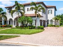 Stunning two-story home featuring a tile roof, arched entryway, lush landscaping, and a brick driveway at 1417 Terralago Pl, Oviedo, FL 32765