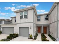 Charming two-story townhouse featuring a one-car garage, neutral paint scheme, and landscaped walkway to the front door at 1900 Erudite Way, Winter Park, FL 32792