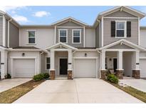 A view of the townhouse exterior with neutral paint, garage, and well-kept landscaping at 2716 Pierr St, Davenport, FL 33837