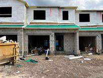 Townhomes under construction with block facade, window openings, and Tyvek wrap, showing a new development project at 4248 Campsite Loop, Orlando, FL 32824