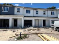 New townhomes under construction with garage and light gray and white siding and trim detail at 4252 Campsite Loop, Orlando, FL 32824