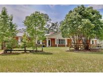 Charming brick home featuring a large front yard with mature trees and a rustic wooden fence at 4802 Anton Ave, Apopka, FL 32712