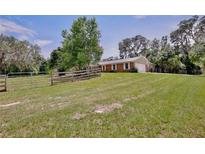Brick home with a well-maintained lawn, complemented by a charming wooden fence and mature trees at 4802 Anton Ave, Apopka, FL 32712