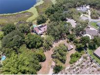 Expansive aerial view of a home near a lake and surrounded by lush greenery and trees, offering privacy at 5671 Cypress Gardens Rd, Winter Haven, FL 33884