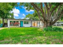 Charming single-story home featuring a modern design, a well-manicured lawn, and a large shade tree at 7616 Simms Ave, Orlando, FL 32812