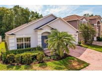 Charming single-story home with a well-maintained lawn, mature palm trees, and a blue front door at 879 Nonastone Run, Casselberry, FL 32707