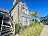Two-story condo with beige siding, large windows, lush landscaping, and metal stairway on a clear, sunny day at 936 Birmingham Ct # 200, Lake Mary, FL 32746