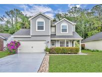 Charming two-story home featuring a manicured lawn, gray siding, and an attached two-car garage at 1576 Crosswind Cir, Orlando, FL 32825