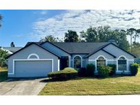 Charming single-story home featuring an attached garage, well-manicured lawn, and large arched windows at 215 Hollowbrook Cir, Daytona Beach, FL 32114