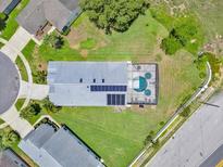 A beautiful aerial view of the home, showcasing the screened pool, solar panels, and spacious lawn at 2627 Autumn Creek Cir, Kissimmee, FL 34747