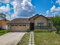 Charming single-story home with a well-manicured lawn and a stone walkway leading to the front door at 2860 Orange Haven Way, Kissimmee, FL 34746
