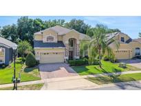 Two-story home with a two-car garage, brick driveway, manicured lawn and lovely landscaping at 33919 Terragona Dr, Sorrento, FL 32776
